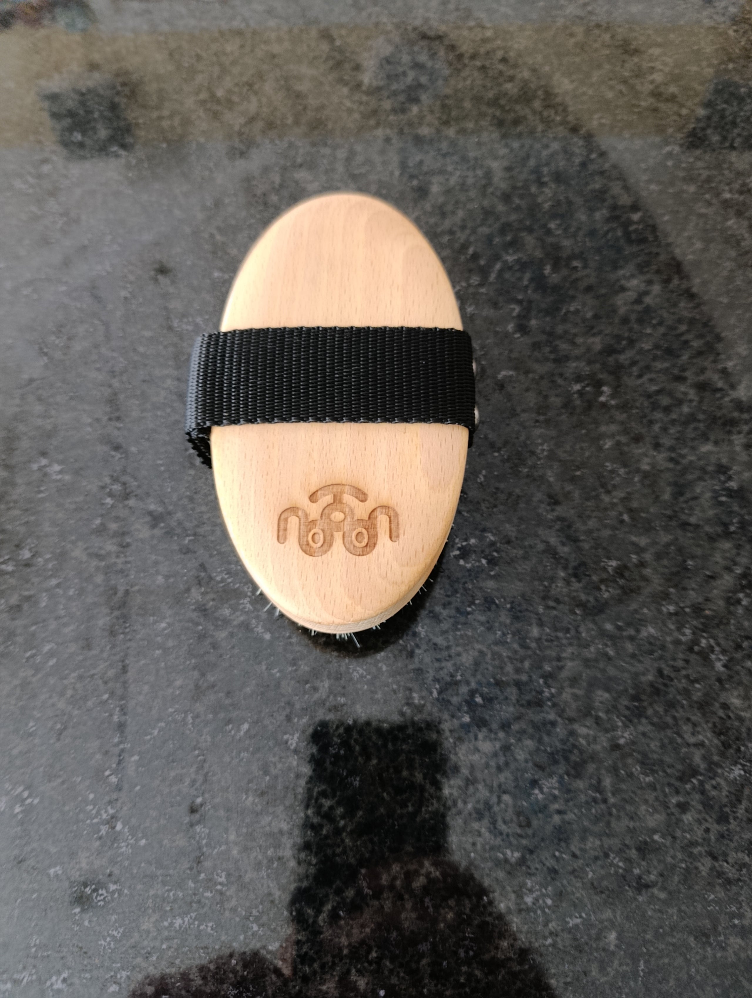 Wooden oval object with a black strap on a textured surface