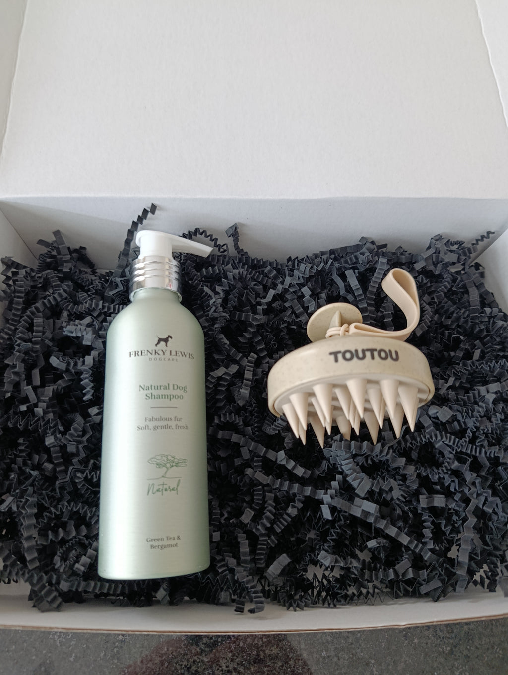Dog grooming product set with shampoo bottle and massage tool in a box.