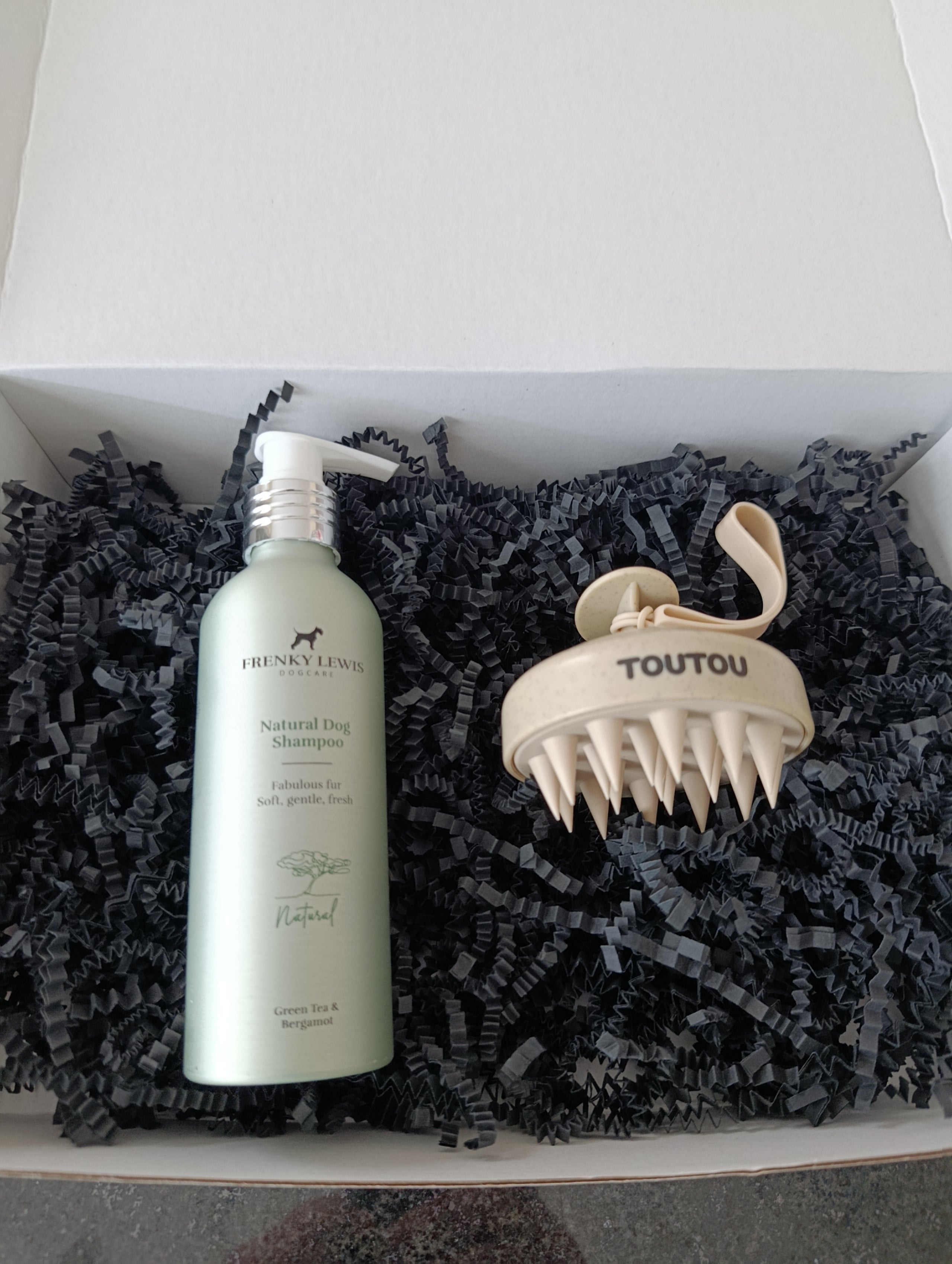 Dog grooming product set with shampoo bottle and massage tool in a box.